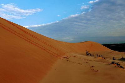 Scenic view of desert against cloudy sky
