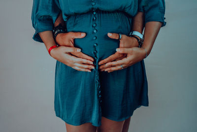 Midsection of pregnant woman with man standing against blue background