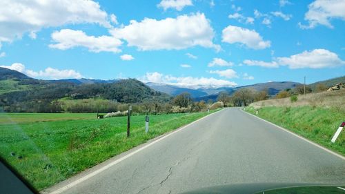 Road amidst green landscape against sky