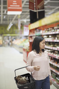 Woman looking at prices during inflation while doing shopping in supermarket