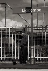 Rear view of man standing on metal fence