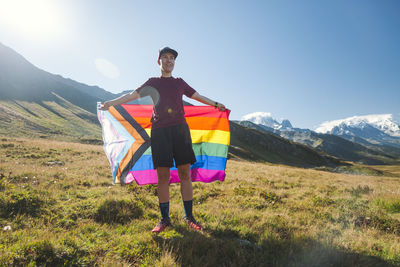 Man holding lgbtiq community flag in mountains