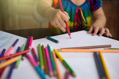 Midsection of man holding pencils on table