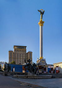 Statue in city against clear blue sky