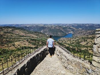 Rear view of man looking at landscape against sky