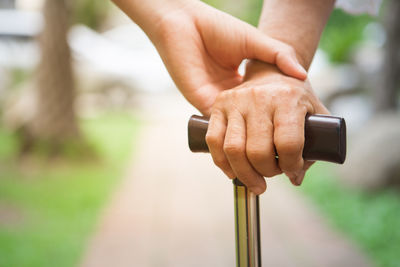 Cropped image of person holding hands with friend on footpath