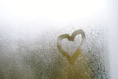Close-up of heart shape on glass against white background