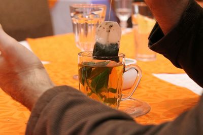 Close-up of hand holding drink on table