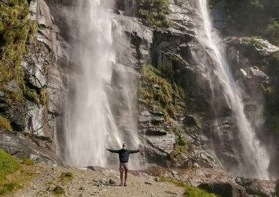 Scenic view of man under waterfall