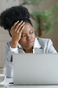 Woman looking away by laptop on table