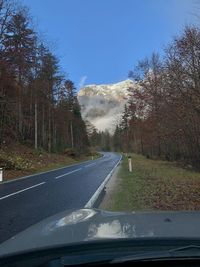 Road amidst trees seen through car windshield