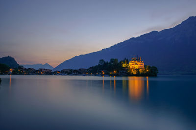 Illuminated building by mountains against sky