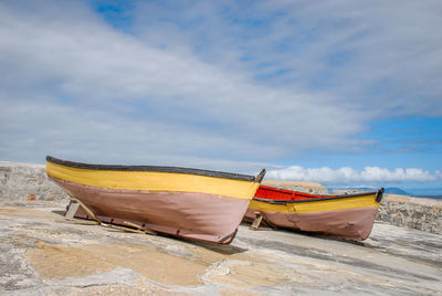 Deck chairs on beach against sky