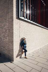 Businesswoman with hand in pocket standing on one leg by office building