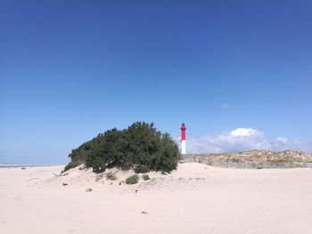 Lighthouse on beach against clear sky