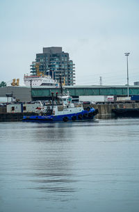 Boats moored at harbor in city against sky