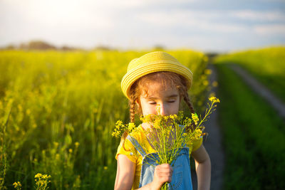 Midsection of person holding yellow flower on field