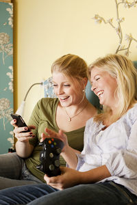 Two young women using mobile phone in bedroom