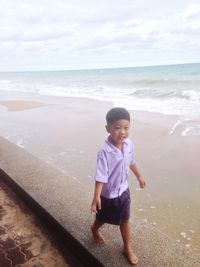 Boy looking away while walking at beach