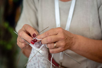 Midsection of woman knitting thread at home