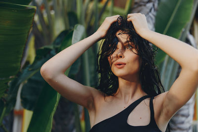 Portrait of young woman standing amidst plants