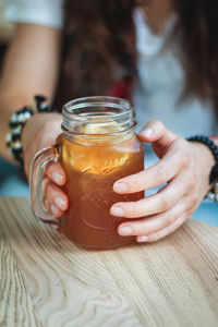 Close-up of woman holding cocktail in drink on table