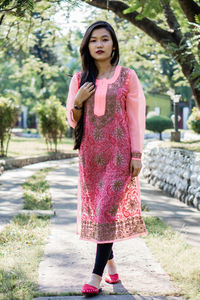 Full length of woman standing against pink wall