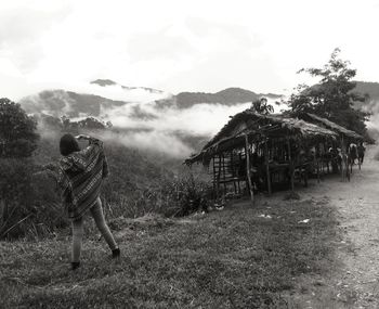 Rear view full length of woman standing against mountain during foggy weather