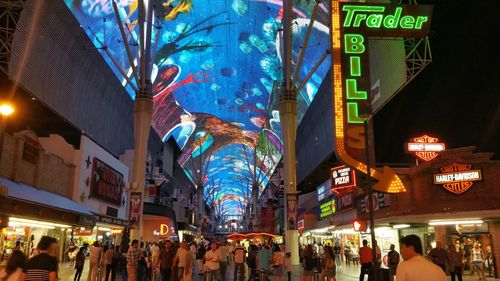 People on illuminated street amidst buildings in city at night