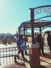 People sitting on railing against clear sky