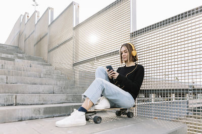 Young woman using mobile phone while sitting on staircase