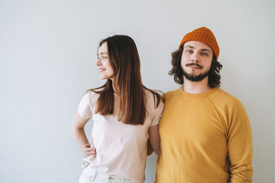 Portrait of smiling couple young family hipsters against gray wall