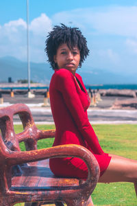 Portrait of young woman sitting on bench at beach