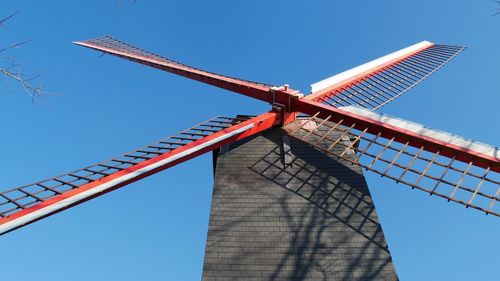 Low angle view of traditional windmill against blue sky in brugge