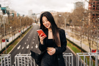 Young woman using mobile phone in city