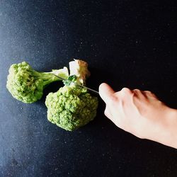 Cropped image of person chopping broccoli on table