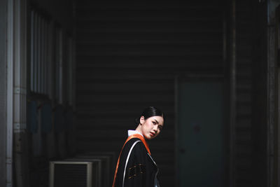 Portrait of woman standing against building