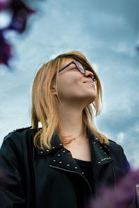 Portrait of a beautiful young woman standing against sky