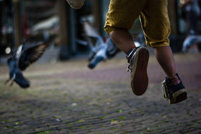 Low section of young boy jumping on the street