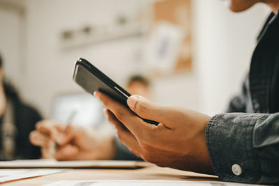 Midsection of man using smart phone on table