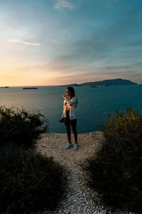 Rear view of woman standing on mountain against sky during sunset