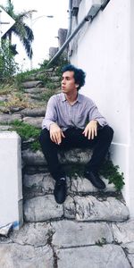 Young man looking away while sitting on staircase