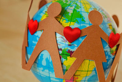 Paper people with hearts in a circle around earth globe - concept of  environmental issues