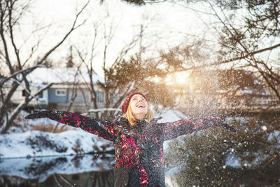 Woman with arms outstretched in snow during winter