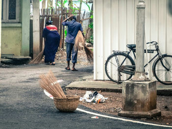 Rear view of woman by man sweeping road