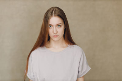 Portrait of young woman standing against wall