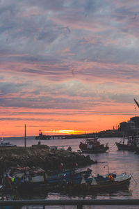 Boats moored at harbor during sunset