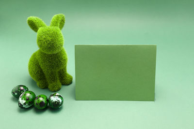 Mockup easter green bunny, rabbit with blue colored chicken quail eggs, empty card for text on blue