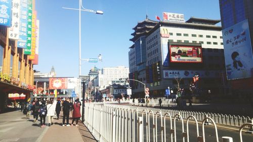 People walking on street amidst buildings in city