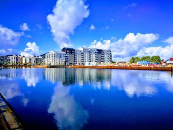 Reflection of buildings in lake against blue sky